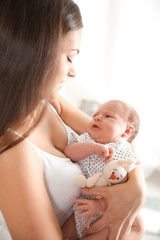 Young woman with her newborn baby on blurred background
