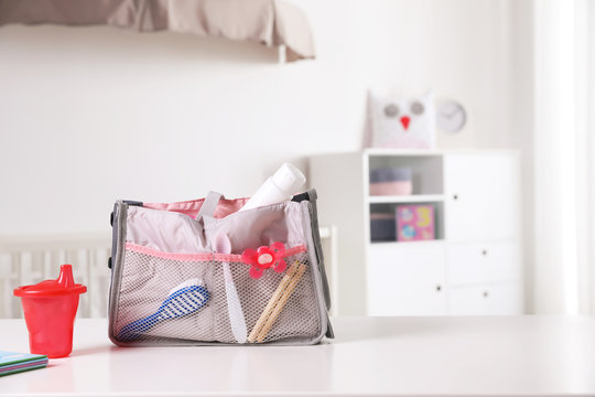 Maternity Bag With Baby Accessories On Table Indoors. Space For Text