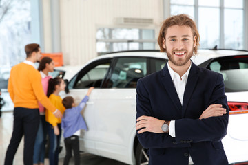 Fototapeta na wymiar Car salesman and blurred family near auto on background