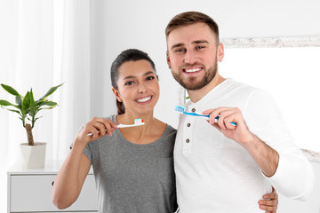 Young couple with toothbrushes in bathroom. Teeth care
