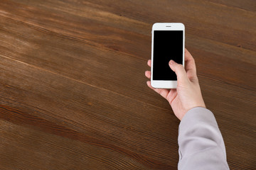 Woman using mobile phone at table, closeup with space for design