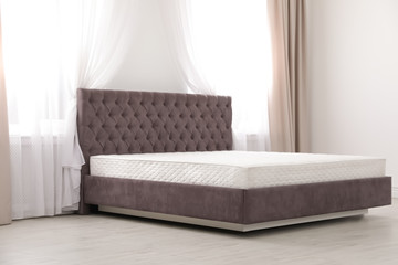 Comfortable bed with new mattress near window in room. Healthy sleep