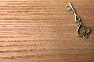 Old vintage key on wooden background, top view with space for text