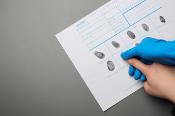 Fototapeta premium Investigator taking fingerprints of suspect on grey background, top view with space for text. Criminal expertise