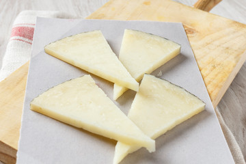 Manchego cheese on wooden board with olives