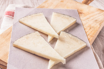 Manchego cheese on wooden board with olives