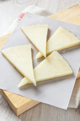 Manchego cheese on wooden board with olives