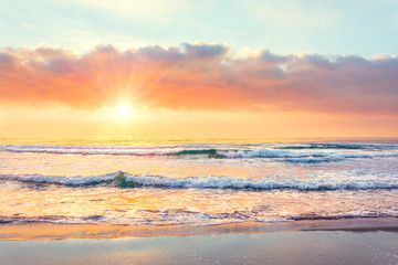 Naklejka na ściany i meble Ocean wave on the beach at sunset time, sun rays.