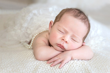 Isolated newborn / infant head resting on arms closeup