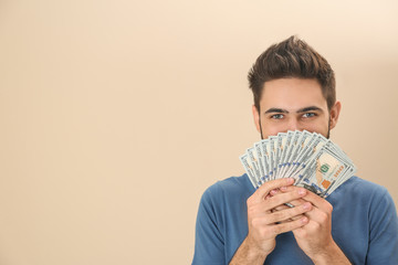 Happy young man with money on color background. Space for text