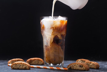 milk pouring into glass of iced coffee