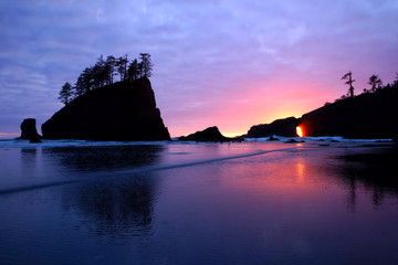 Sunset over the Pacific through sea arches at a beach in Olympic National Park, Washington, USA