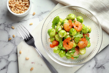 Bowl of delicious salad with Brussels sprouts and shrimps on marble table, top view