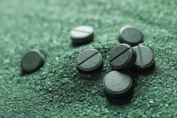 Natural green spirulina powder and pills as background, closeup