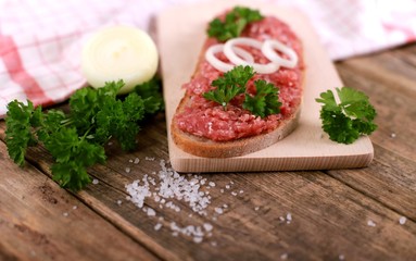 slice of bread with minced meat, parsley and onions - on rustic wooden table - breakfast bread - pork mett