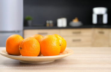 Fresh oranges on wooden table in kitchen. Space for text