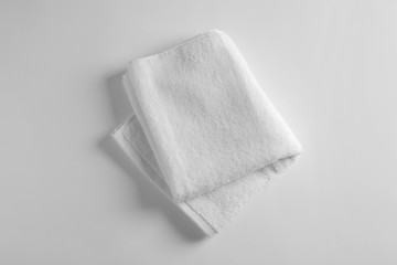 Folded soft terry towel on light background, top view