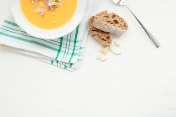 Pumpkin soup and organic pumpkins, top view, copy space. Seasonal autumn food - Spicy pumpkin soup with croutons and pumpkin seeds.