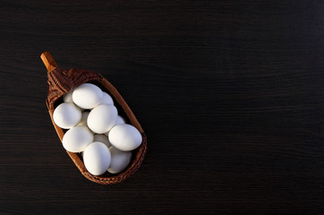 Easter eggs in the Duck basket. wicker basket of straw. festive meal on a dark wooden table.