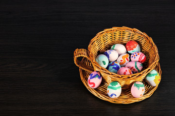 Easter eggs in the basket. wicker basket of straw. festive meal on a dark wooden table.