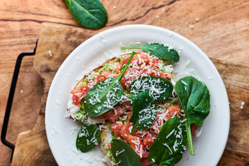 Homemade italian bruschetta with avocado, salmon, spinach and parmesan cheese top view