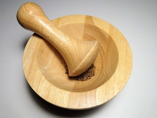 Mörser und Stößel aus Holz vor weißem Hintergrund