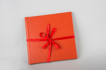 Red book with red ribbon. Red gift on a wooden background