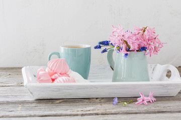 A cup of coffee and a bouquet of flowers on a wooden table