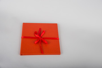 Red book with red ribbon. Red gift on a wooden background