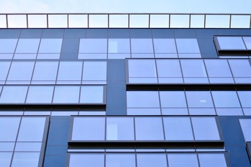 New office building in business center. Wall made of steel and glass with blue sky. 