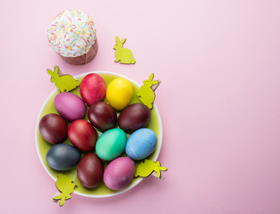 Colorful Easter eggs and Easter bread attributes of Easter celebration. Pink background.