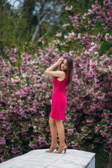 Young girl stand in front of sakura tree. Spring outside. Pink Blossom tree