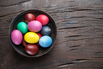 Fototapeta na wymiar Colorful Easter eggs in bowl on wooden table. Attribute of Easter celebration.