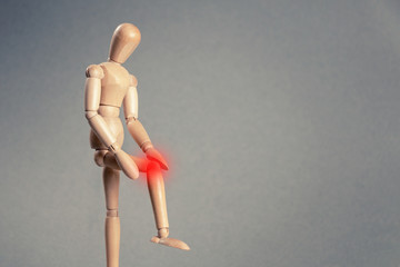 Wooden man with knee pain. Copy space.