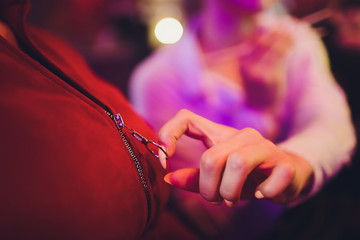 the girl's hand fastens the zipper on the jacket outdoor. woman's hand fastens the zipper on the coat closeup.