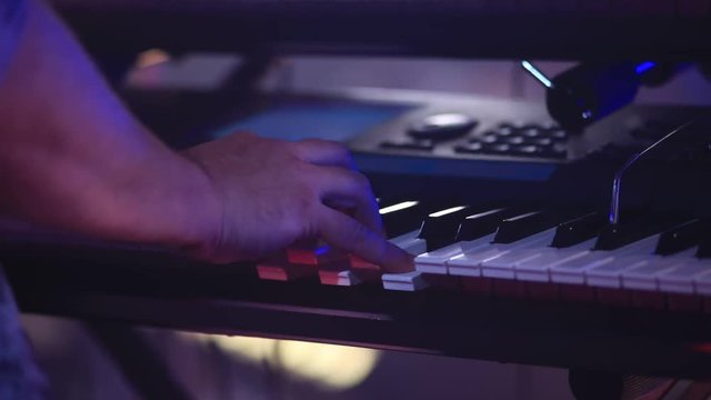 hands of a man playing an electronic piano