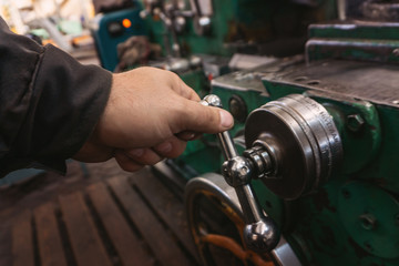 The hand of the machine operator creates a mechanical switch on the lathe.