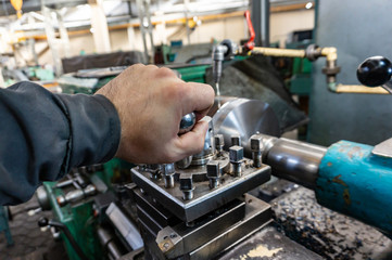 The hand of the machine operator creates a mechanical switch on the lathe.