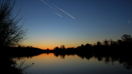 Abendrot am Fluss mit Kondensstreifen