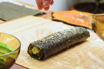 Women's hands close-up in a restaurant sprinkle sesame oil during the preparation of sushi