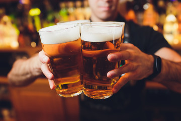 Barman hands pouring a lager beer in a glass.