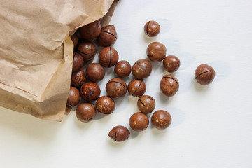 Organic macadamia nuts in craft bag on white table 