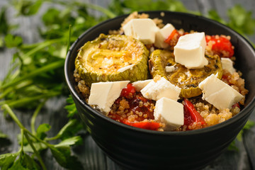 Baked vegetable salad with cheese and quinoa on the black table. Vegetarian dish. Natural plant food. The view from the top.