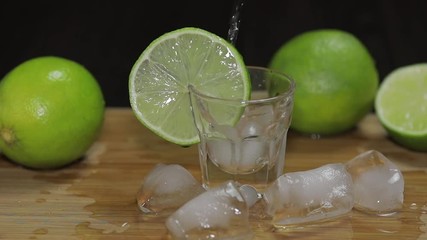 Pour vodka or tequila into shot glasses with ice cubes