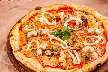 Italian Pizza with seafood and mozzarella cheese on wooden cutting board. Close up