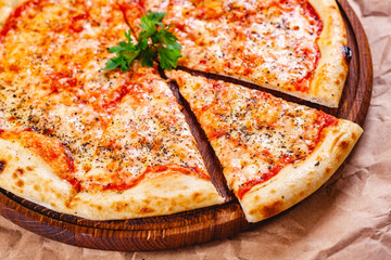 Italian Pizza Margherita with tomatoes and mozzarella cheese on wooden cutting board. Close up