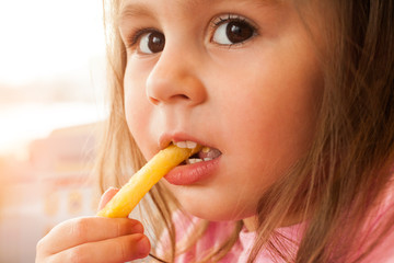 Little child eating a french fries in the cafe