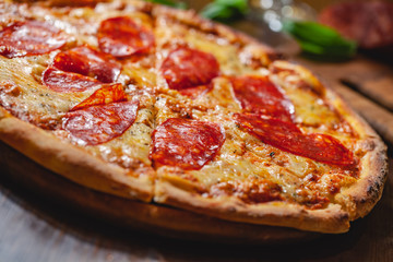 Italian Pepperoni pizza with mozzarella cheese and salami on wooden board. Close up