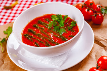 Tomato cold gazpacho soup with pesto sauce in white bowl. Close up