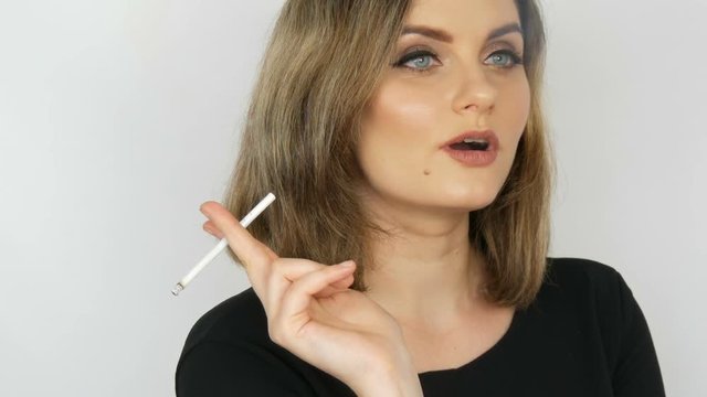 Beautiful sexy girl a bitch with flowing hair and blue eyes smokes a thin cigarette on a white background